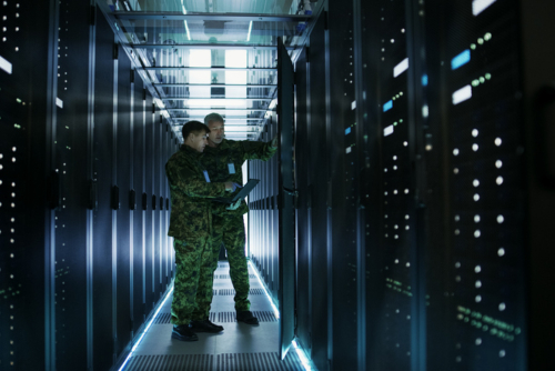 In Data Center Two Military Men Work with Open Server Rack Cabinet. 